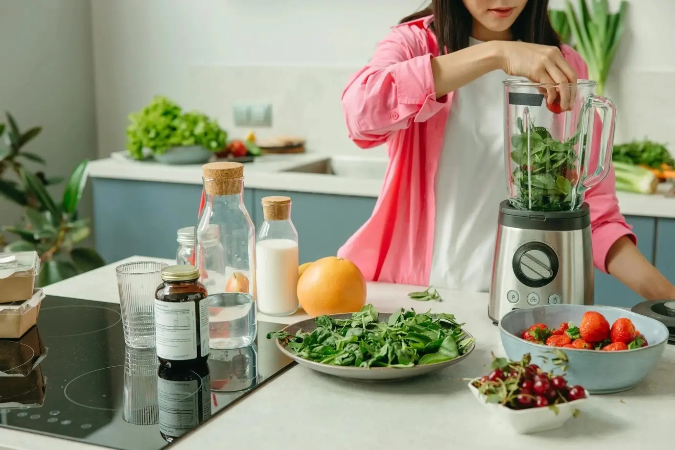 woman making a smoothie at the kitchen counter