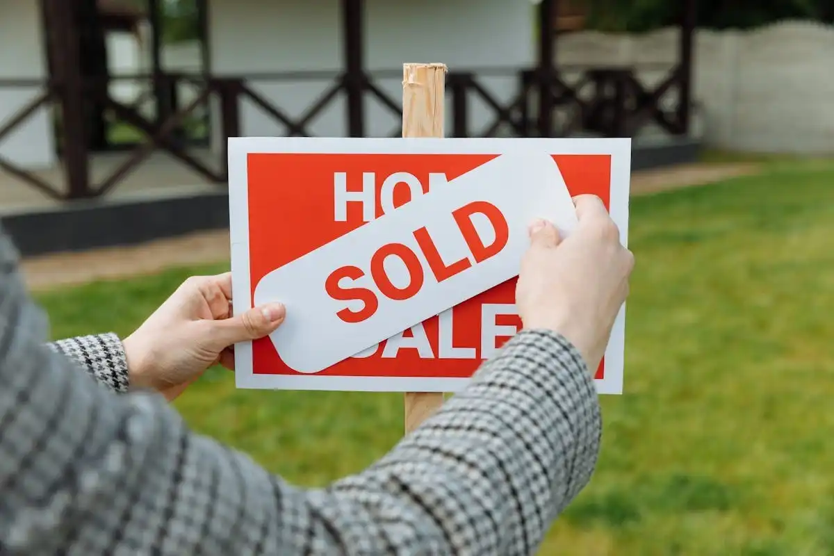A real estate agent pasting sold sticker on top of house for sale sticker A real estate agent pasting sold sticker on top of house for sale sticker