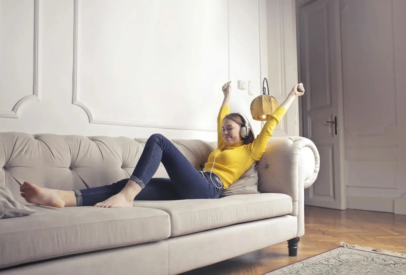woman enjoying music sitting on a couch