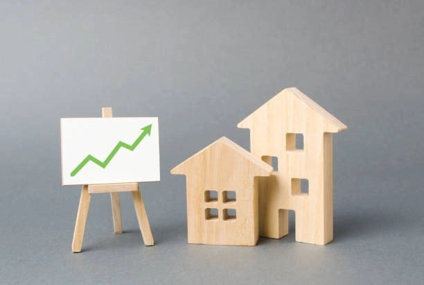 Two wooden houses and a green up arrow sign on an easel board Two wooden houses and a green up arrow sign on an easel board