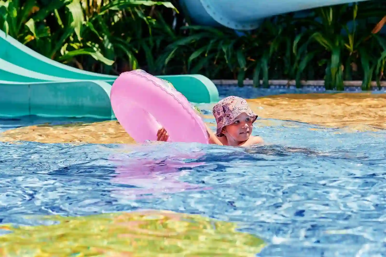 A boy swimming in a pool while holding a floater.