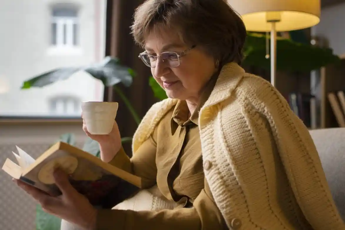 An elderly woman relaxing with a coffee while reading a book. An elderly woman relaxing with a coffee while reading a book.