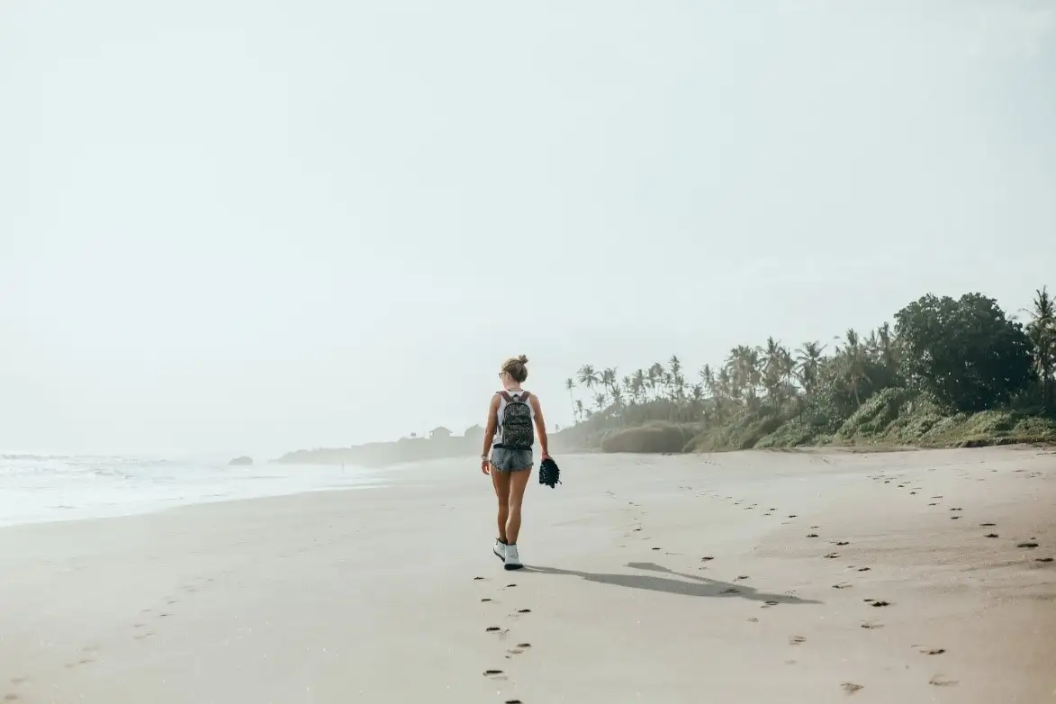 A woman walking on a beach in Goa.