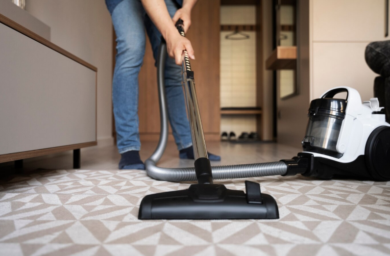 A man cleaning the carpet with a vacuum cleaner. A man cleaning the carpet with a vacuum cleaner.