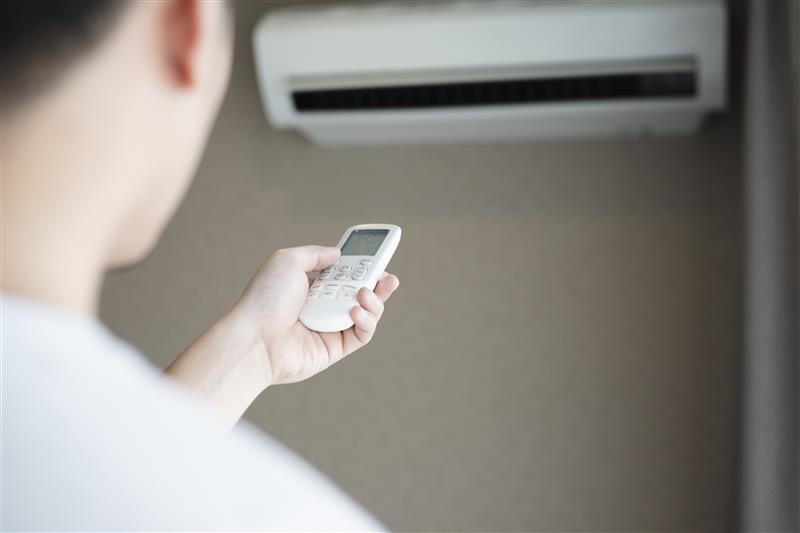 A man turning the air conditioning on with the remote. A man turning the air conditioning on with the remote.