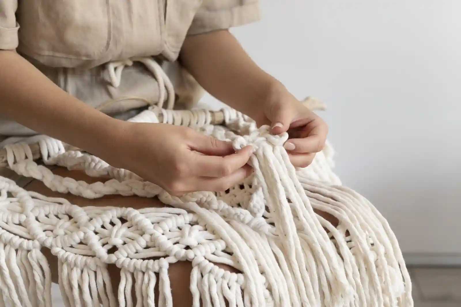 A person making a macrame wall hanging.