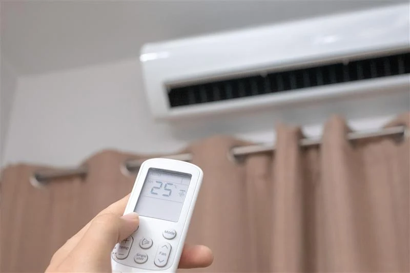 A hand holding up the AC remote to control the temperature during summers in Goa.