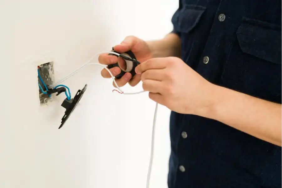 A man repairing a faulty outlet, a crucial step in maintaining your property in Goa during the monsoon.