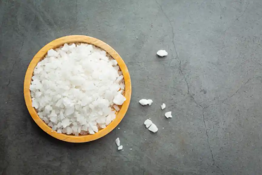 A bowl of sea salt against a grey background.