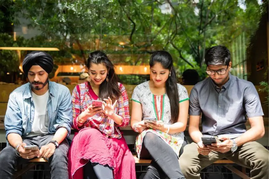 Group of Gen Z adults and potential young homebuyers, using their smartphones in a lifestyle-oriented setting like a property in Goa.