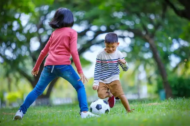 Two kids playing football in a playground in Goa.