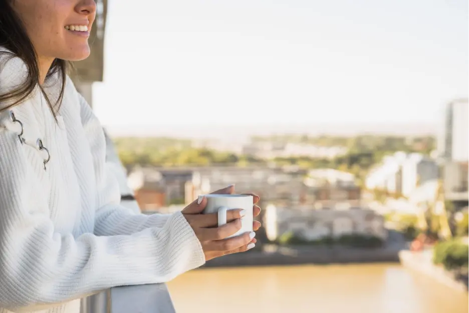 A woman holding a coffee cup in the balcony of her home in Goa.