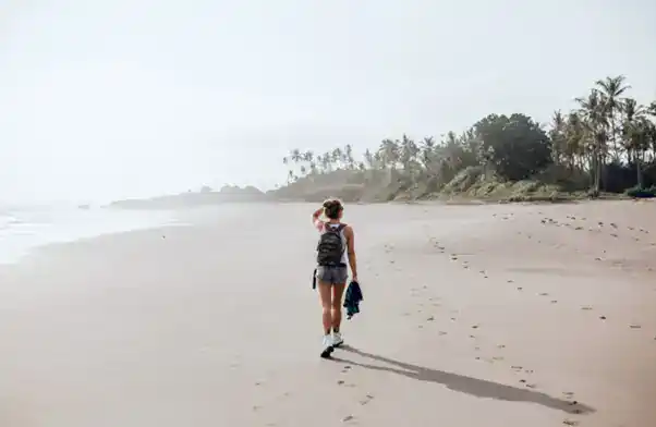A girl walking on a beach in December in Goa.