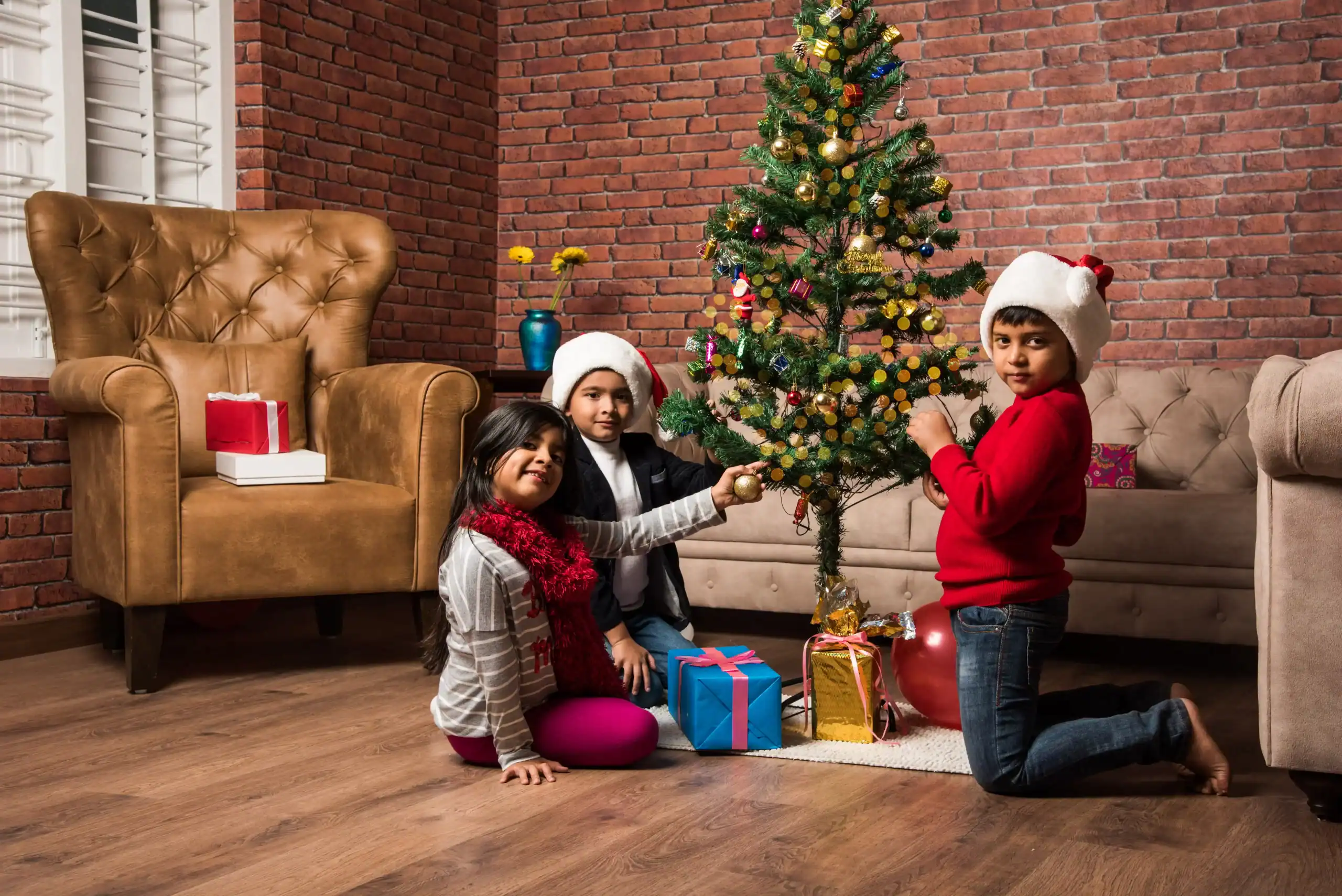 Children sitting in front of the Christmas tree in their home in Goa