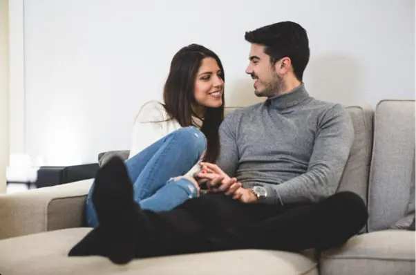 A couple sitting on a couch in their home in Goa and relaxing.