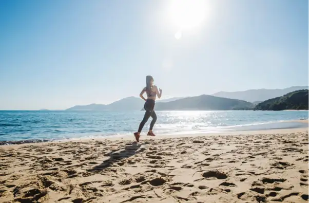 A woman taking a morning run on a beach near a home in Goa